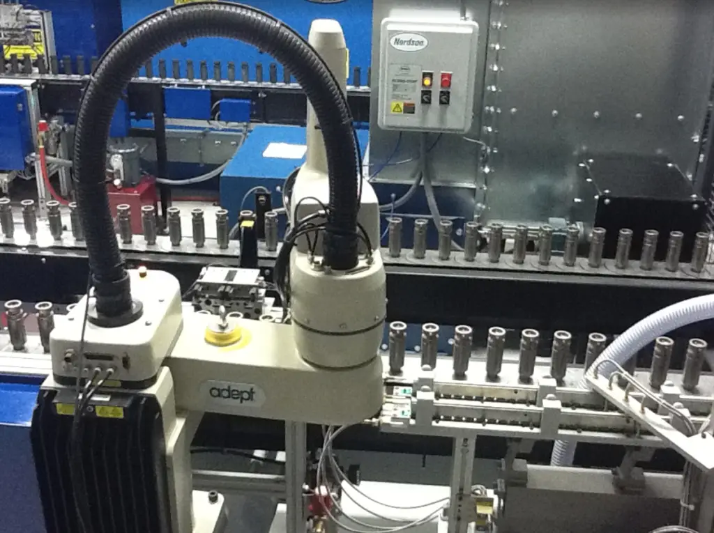Pick-and-place robotic masking system integrated into an automated finishing line with conveyor and fluid handling equipment.