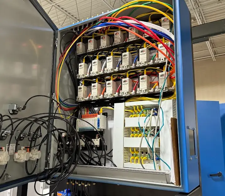 Open pneumatic control panel showing valve manifolds, solenoids, and airline routing for an automated finishing system.