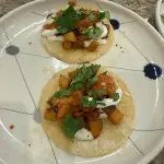 Chorizo con papas tacos topped with seared jalapeño salsa, melted Oaxaca, sour cream, and cilantro on corn tortillas.