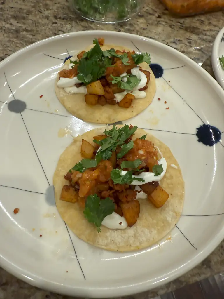 Chorizo con papas tacos topped with seared jalapeño salsa, melted Oaxaca, sour cream, and cilantro on corn tortillas.