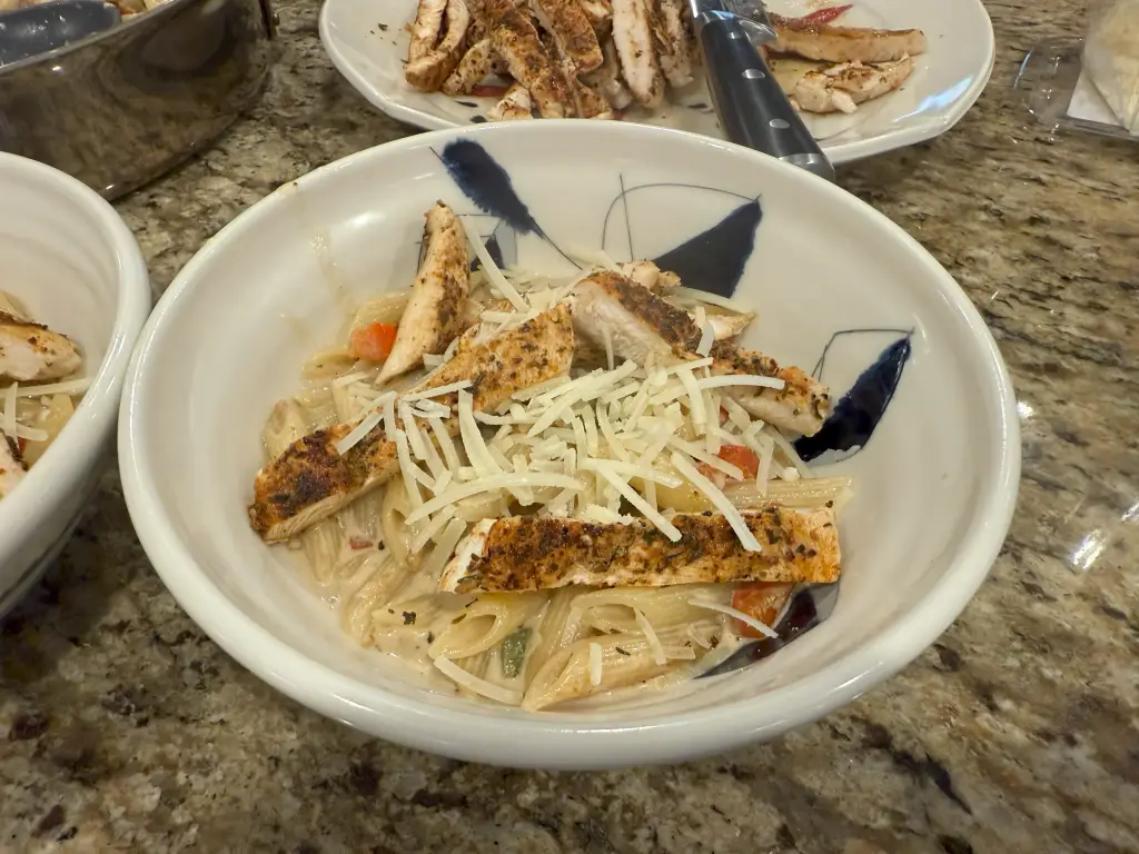 A skillet of creamy spicy Cajun chicken Alfredo pasta topped with fresh parsley and Parmesan, with a rich, golden sauce coating every noodle.