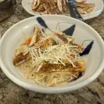 A skillet of creamy spicy Cajun chicken Alfredo pasta topped with fresh parsley and Parmesan, with a rich, golden sauce coating every noodle.