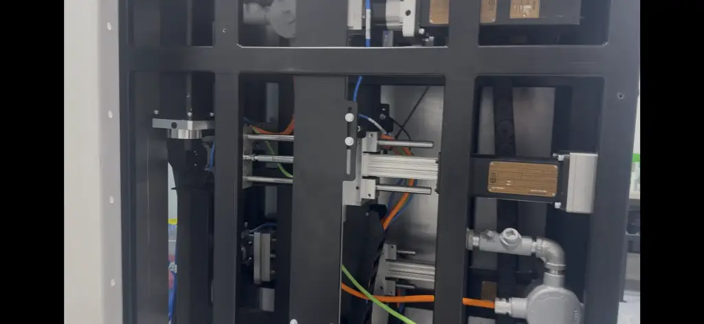 Close-up view of an automated explosion-proof spray gun positioner showing the servo motors, linkages, and internal mechanical components that drive 3-axis spray gun positioning inside a hazardous-duty paint booth.