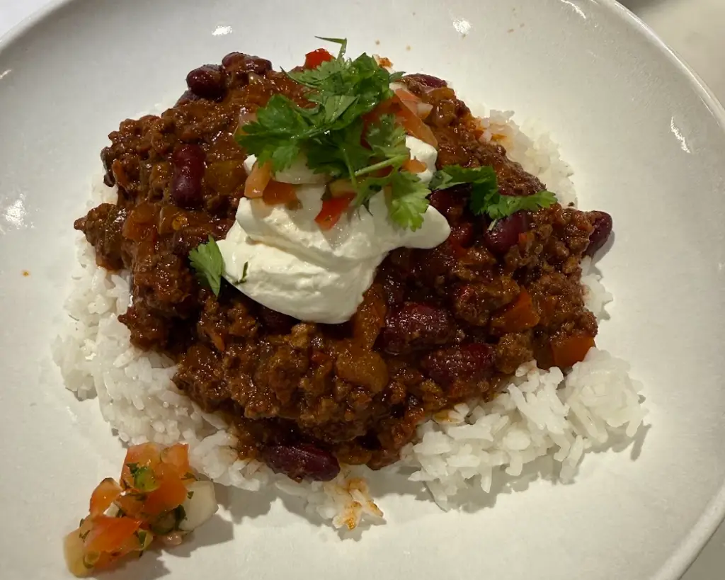 Spicy ground beef chili con carne served over white rice with fresh pico de gallo and sour cream.