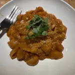 Shortcut one-pot sausage bolognese with lumache pasta, Parmesan, and fresh basil in a bowl