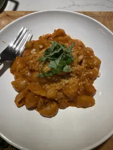 Shortcut one-pot sausage bolognese with lumache pasta, Parmesan, and fresh basil in a bowl